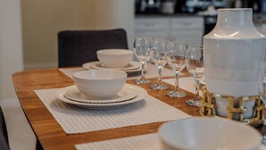 A dining table set with white dinnerware, including bowls and wine glasses, in a modern kitchen setting. - Go!#41 - WINDSOR AT WESTSIDE (Kissimmee)