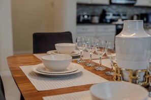 A dining table set with white dinnerware, including bowls and wine glasses, in a modern kitchen setting. - Go!#41 - WINDSOR AT WESTSIDE (Kissimmee)