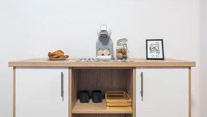 A kitchenette with a coffee maker, a jar of coffee beans, a framed coffee bar illustration, and a plate of croissants. - Casa De Invitados El Rincon De Itara (Firgas)