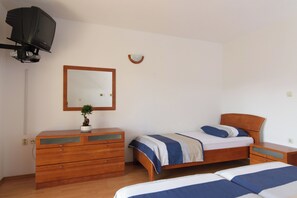 Ein Schlafzimmer mit einem hölzernen Schminktisch, einem Bett mit blauen und weißen Streifen sowie einem kleinen Topfpflanzen auf dem Schminktisch.