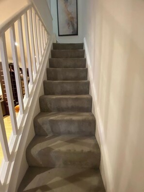 Eine Treppe mit weißer Brüstung und Teppichstufen, die zu einer Zwischenebene führen.