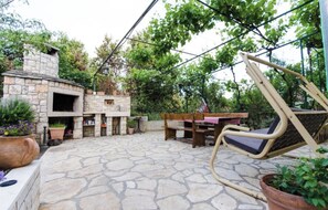 A stone patio with a stone fireplace, outdoor furniture, and potted plants. - A 3 apt w shared pool and balcony, near the beach (Seget Vranjica)