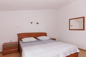 Ein Schlafzimmer mit Holz-Kopfteil, zwei Nachttischen, einem Bett mit gemusterten Kissen, einem Spiegel und einer Steckdose.