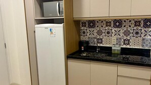 Een kleine keuken met een koelkast, een spoelbak en een magnetron.