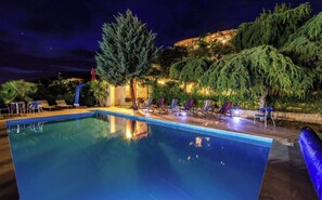 A nighttime pool area with a clear pool, lounge chairs, and a building in the background. - A 4 apt w shared pool and balcony, near the beach (Seget Vranjica)