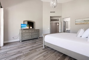 Ein Schlafzimmer mit Bett, Kommode, Fernseher und einer Chandelier.