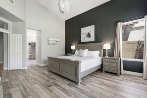 A bedroom with a bed, bedside tables, a chandelier, and a large window with curtains. - Grayhawk Scottsdale Retreat - Private Pool and Spa (Scottsdale)