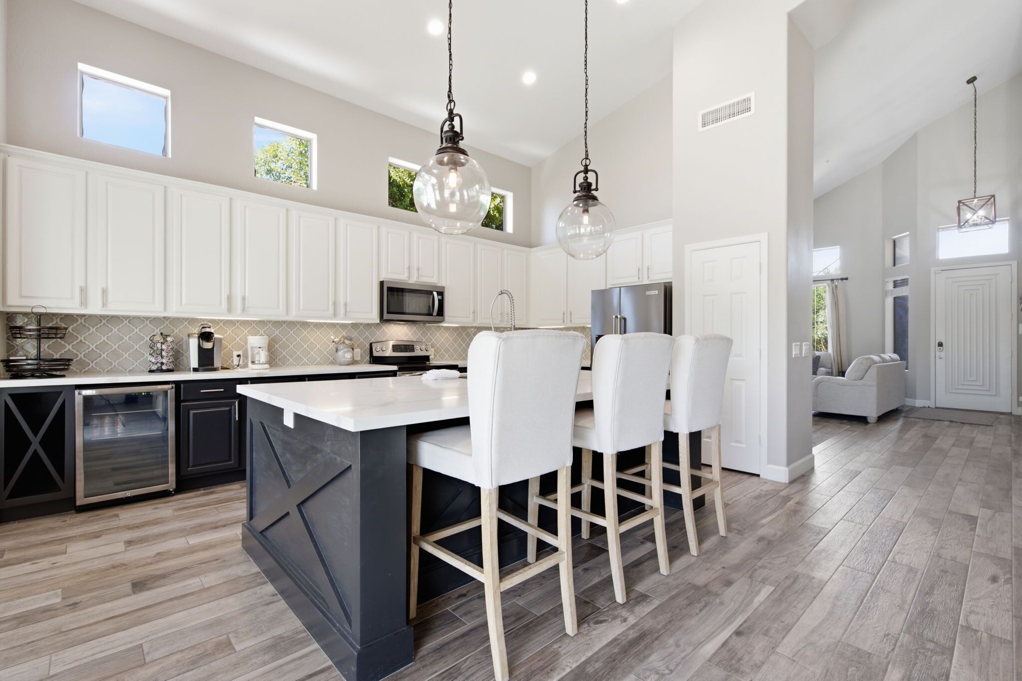 A modern kitchen with white cabinetry, a central island, and bar stools.