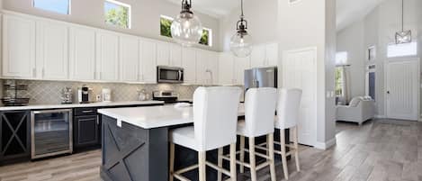 A modern kitchen with white cabinetry, a central island, and bar stools.