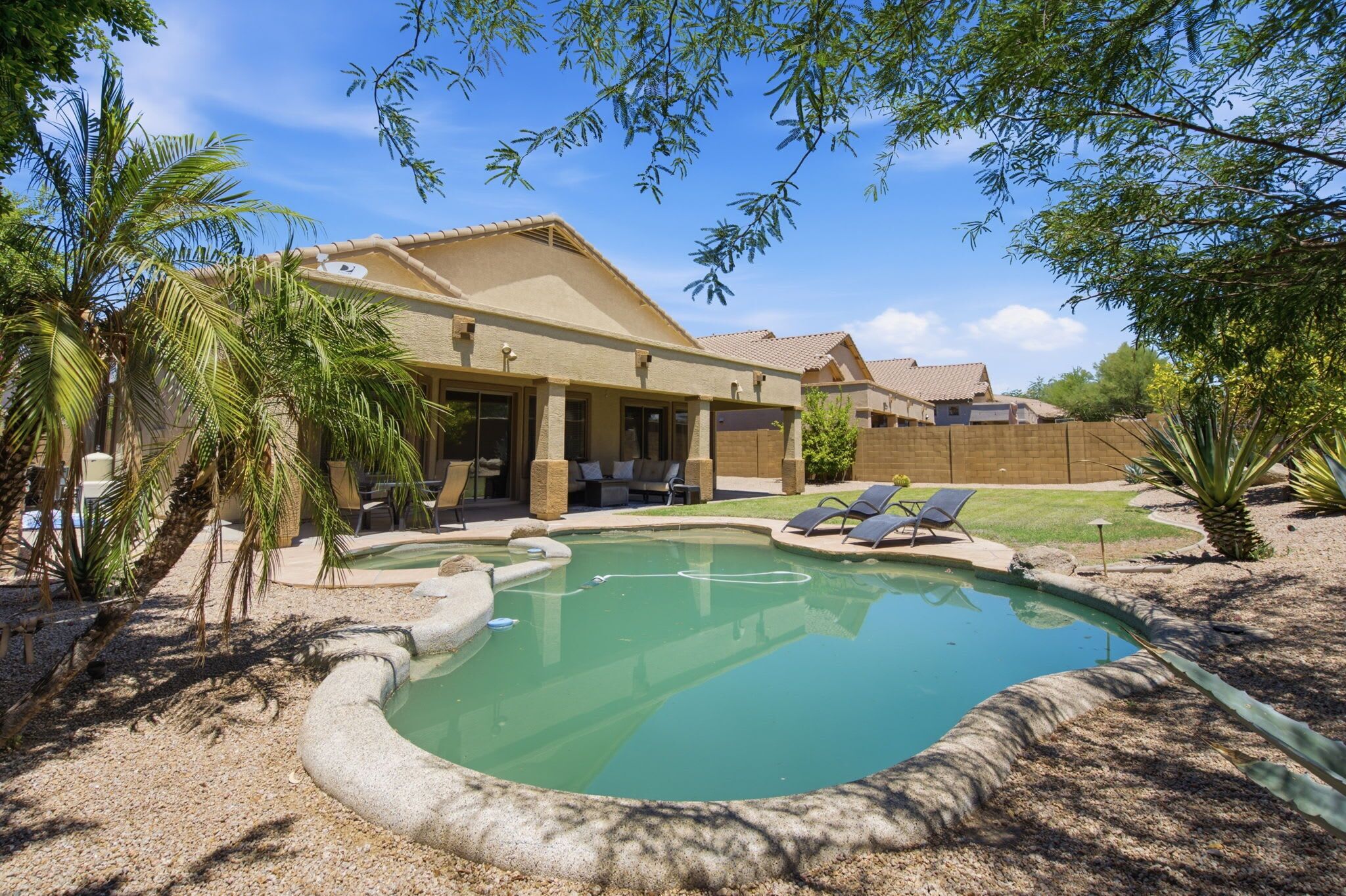 Una propiedad residencial con piscina, mobiliario exterior y terraza cubierta.
