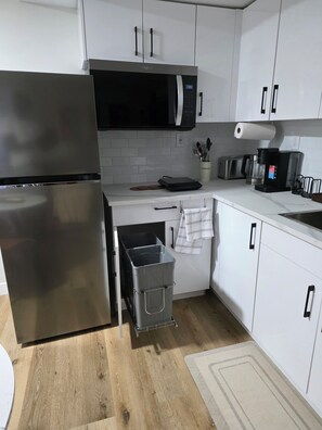 Una cocina moderna con un refrigerador de acero inoxidable, un microondas y una cafetera.