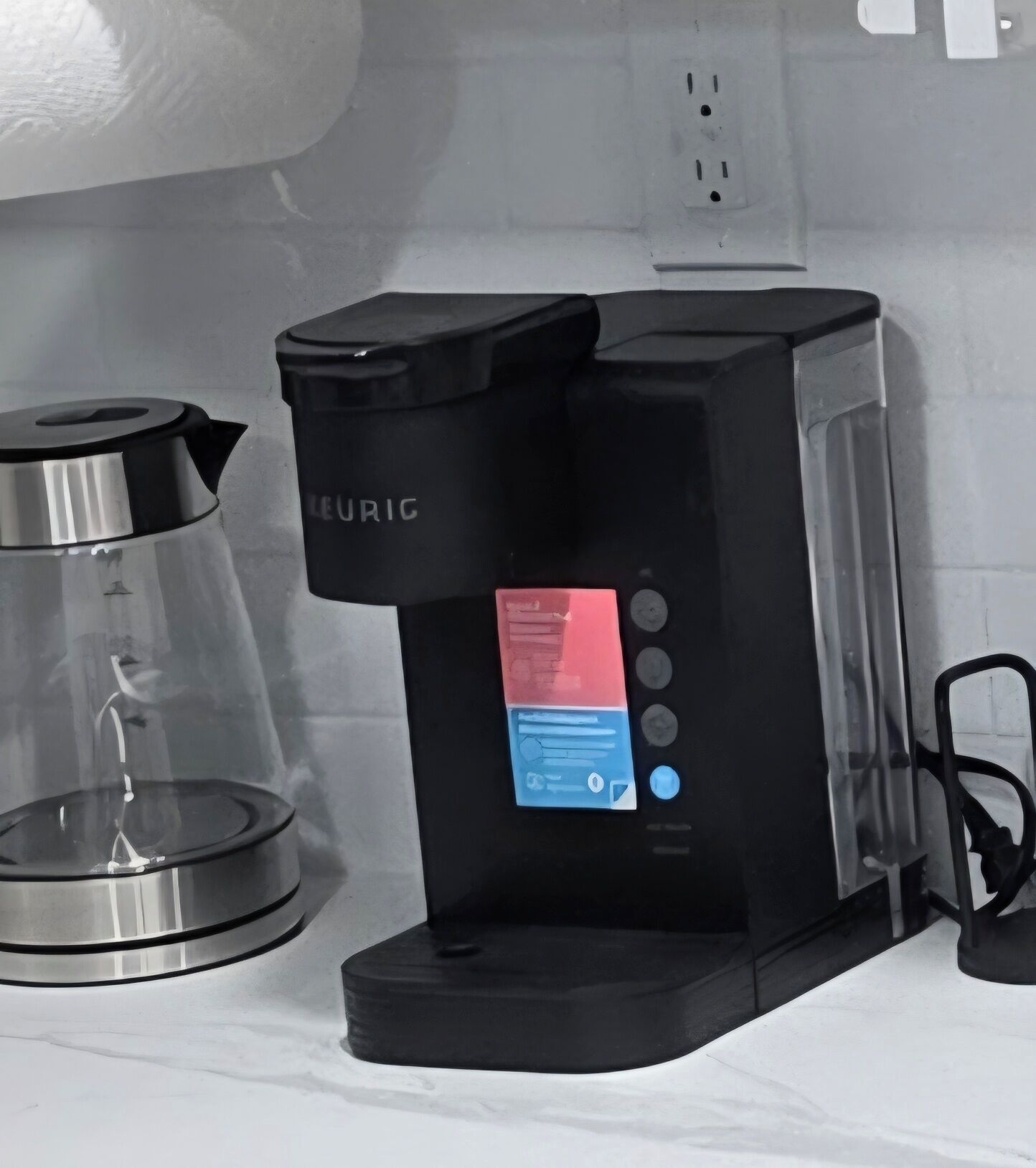 A black coffee maker with a digital interface on a kitchen counter.
