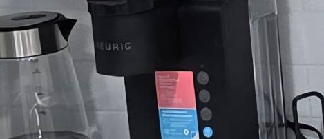 A black coffee maker with a digital interface on a kitchen counter.