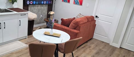 A modern living space with a dining area, a red sofa, and a flat-screen TV displaying a streaming service interface.
