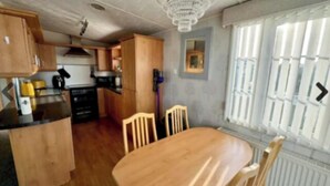 Una cocina compacta con armarios de madera, una mesa de comedor con sillas y una ventana con persianas.
