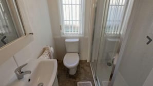 Un baño con lavamanos, inodoro y cabina de ducha blancos.