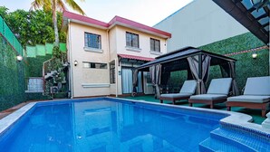 A swimming pool with lounge chairs, a covered seating area, and a building with a red roof. - Fantastic 6-bedroom resort with AC in sunny San Salvador, Luxury house villa (San Salvador)
