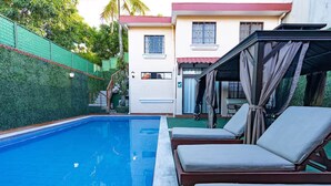 A swimming pool with lounge chairs, a covered area, and a building with a door and windows. - Fantastic 6-bedroom resort with AC in sunny San Salvador, Luxury house villa (San Salvador)