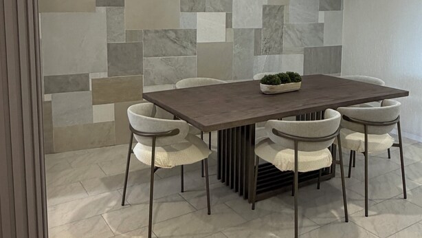 A dining area with a rectangular table, six chairs, and a decorative wall with a mosaic pattern. - Katarma Deluxe Apartments (Puerto Baquerizo Moreno)