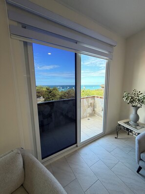 Ein Zimmer mit einer großen Schiebeglasdoor, die auf einen Balkon mit Blick auf das Meer und Boote führt.