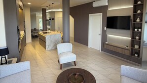 A modern living room with a marble island, a television mounted on the wall, and a seating area with a coffee table. - Katarma Deluxe Apartments (Puerto Baquerizo Moreno)