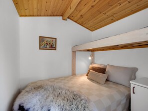 Een slaapkamer met een stapelbed, een pluizig vloerkleed, een schilderij aan de muur en een klein wit kastje.