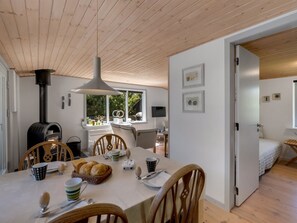 Een gezellig eetgedeelte met een houten tafel, stoelen en een groot raam.