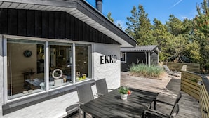 En modern byggnad med ett stort glasfönster, en träveranda och en skylt med texten ”EKKO”.