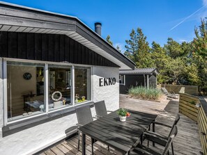 Een modern gebouw met een groot raam, een houten terras en een bord waarop 'EKKO' staat.