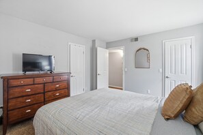 A bedroom with a bed, dresser, television, and a door leading to another room. - Fully furnished, 1-bedroom condo in the heart of Tempe. (Tempe)