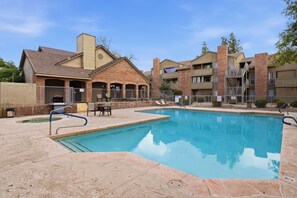A swimming pool with lounge chairs and a barbecue area, surrounded by brick buildings with balconies. - Fully furnished, 1-bedroom condo in the heart of Tempe. (Tempe)
