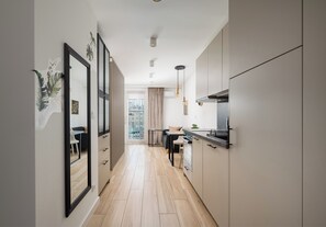 A modern kitchen with a central island, wooden flooring, and a view to the outside. - Rondo ONZ Signature Studio (Warszawa)