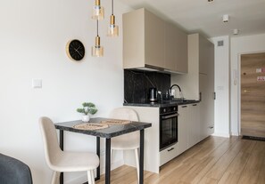 A modern kitchen with a black countertop, stainless steel appliances, and a wooden floor. - Rondo ONZ Signature Studio (Warszawa)