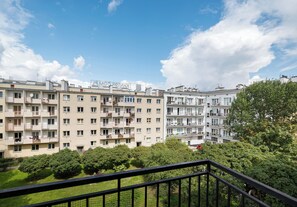 Un edificio residencial de varios pisos con balcones, cielo despejado y vegetación circundante.