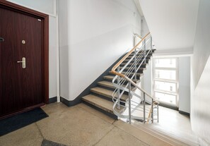 Eine Treppe mit hölzernem Geländer und Metallspindeln, die zu einer oberen Etage führt.