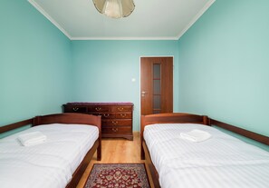 A room with two wooden beds, a dresser, and a door. - Metro Targówek Heritage Apartment (Warszawa)