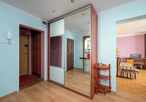 A room with a sliding door leading to another space, a wooden floor, a small wooden table, and a chair. - Metro Targówek Heritage Apartment (Warszawa)