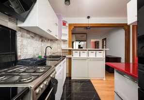 Una cocina moderna con estufa a gas, piso de mármol negro y muebles de cocina blancos.