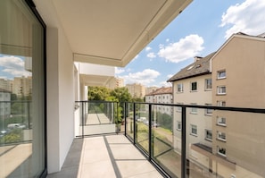 Un balcon doté d’une balustrade en verre, donnant sur un quartier résidentiel composé de plusieurs immeubles.