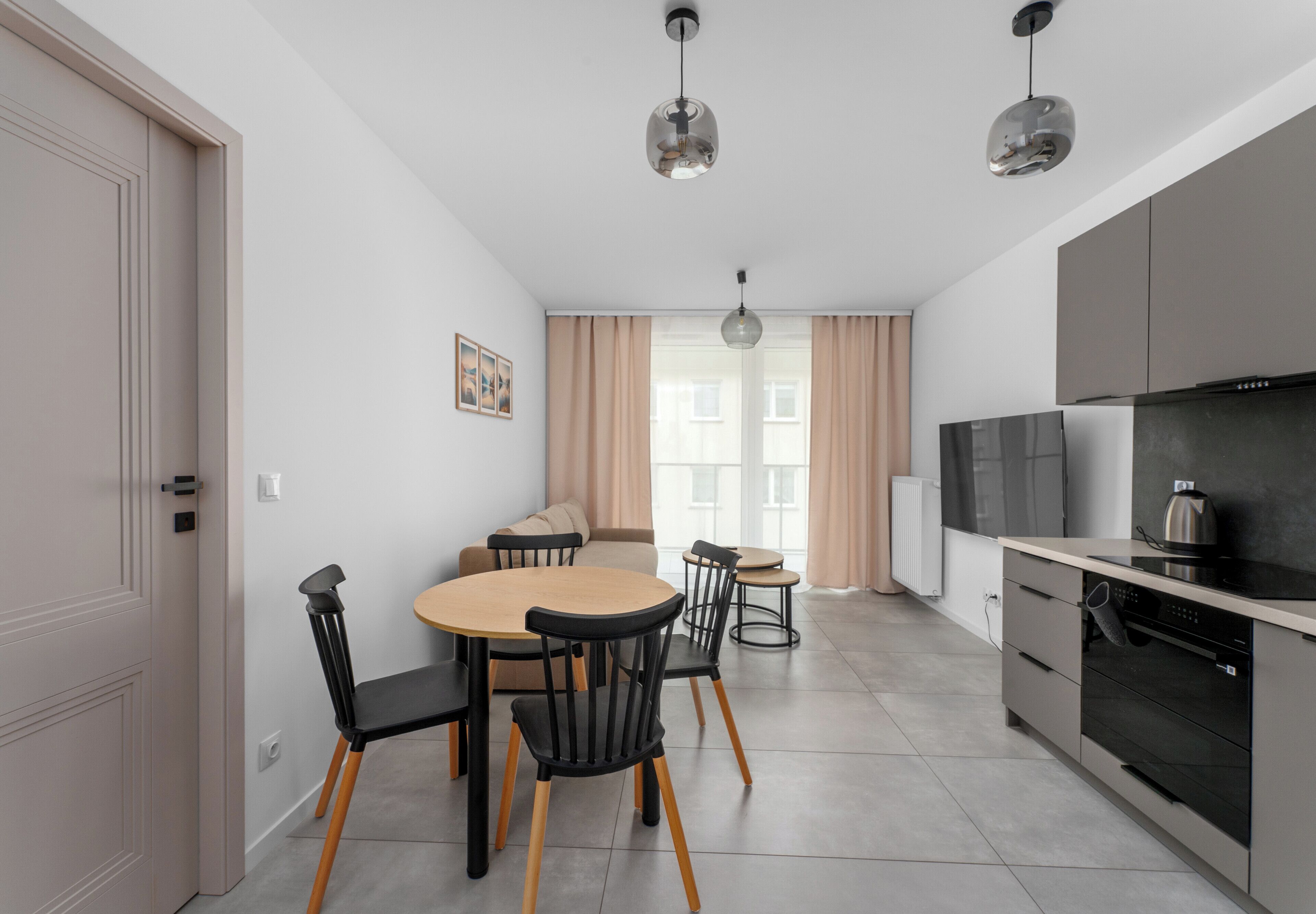 Une cuisine moderne avec un coin repas, comprenant une table avec des chaises, un réfrigérateur et une bouilloire.