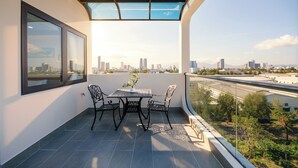 En balkon med et bord, stole, en potteplante og udsigt over byen.