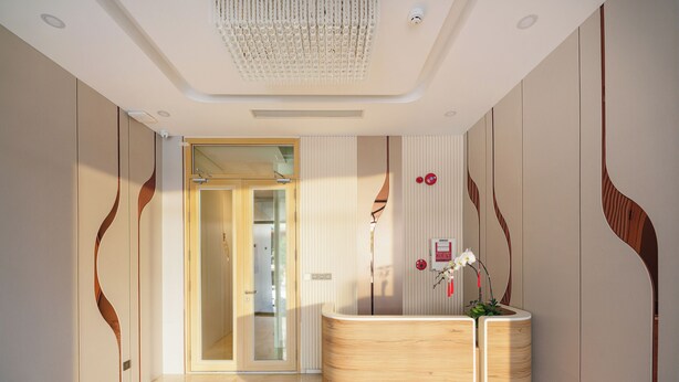 Et moderne interiør med en receptionsdisk, en glasdørindgang og et dekorativt loft.