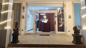 A hotel entrance with a reception desk, a sign with the hotel's name, and two statues on either side. - Moonrise Rooms (Pecatu)