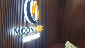A reception desk with a wooden panel wall and a laptop on it. - Moonrise Rooms (Pecatu)