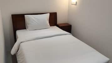 A single bed with a wooden headboard, a bedside table, and a wall-mounted light fixture.