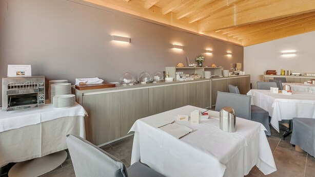 A restaurant with a wooden ceiling, a buffet counter, and tables set for dining.