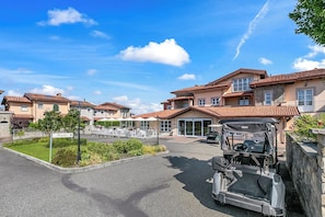 Un hotel con varias construcciones, una zona de recepción, asientos al aire libre y un carrito de golf.