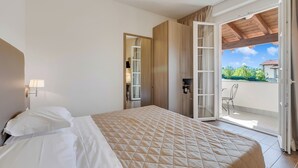 A hotel room with a bed, a desk, a chair, and a view of the outdoors.