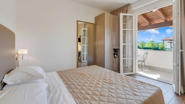 A hotel room with a bed, a desk, a chair, and a view of the outdoors.