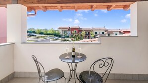 Un balcón con una mesa y dos sillas, con vista a una zona residencial con casas y una calle.